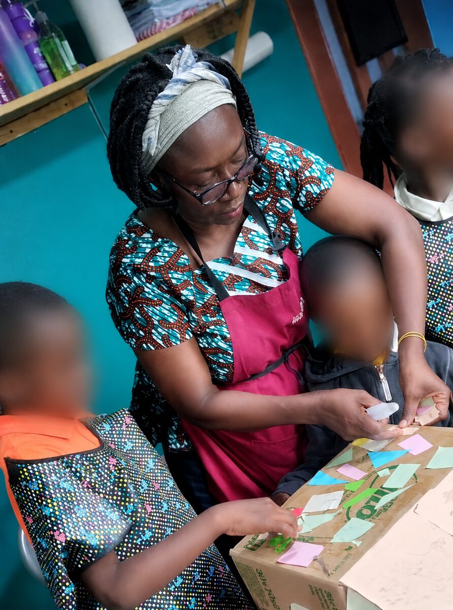 Elorm and children working together on a hands-on collaborative art project.
